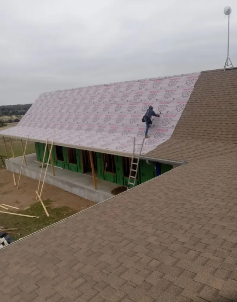 Worker preparing underlayment for a metal roof installation in Blakely